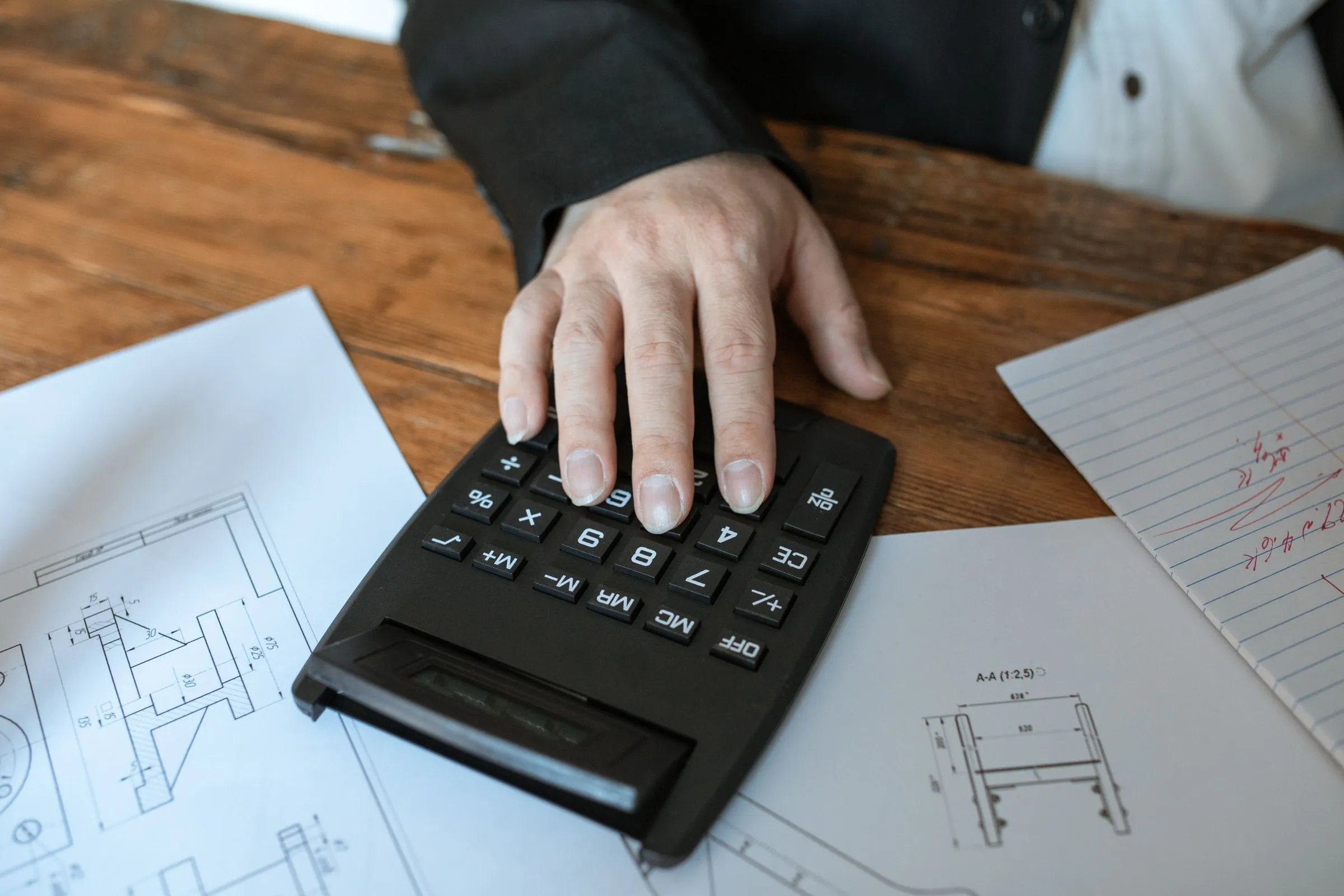Persona haciendo cuentas con una calculadora sobre unos documentos