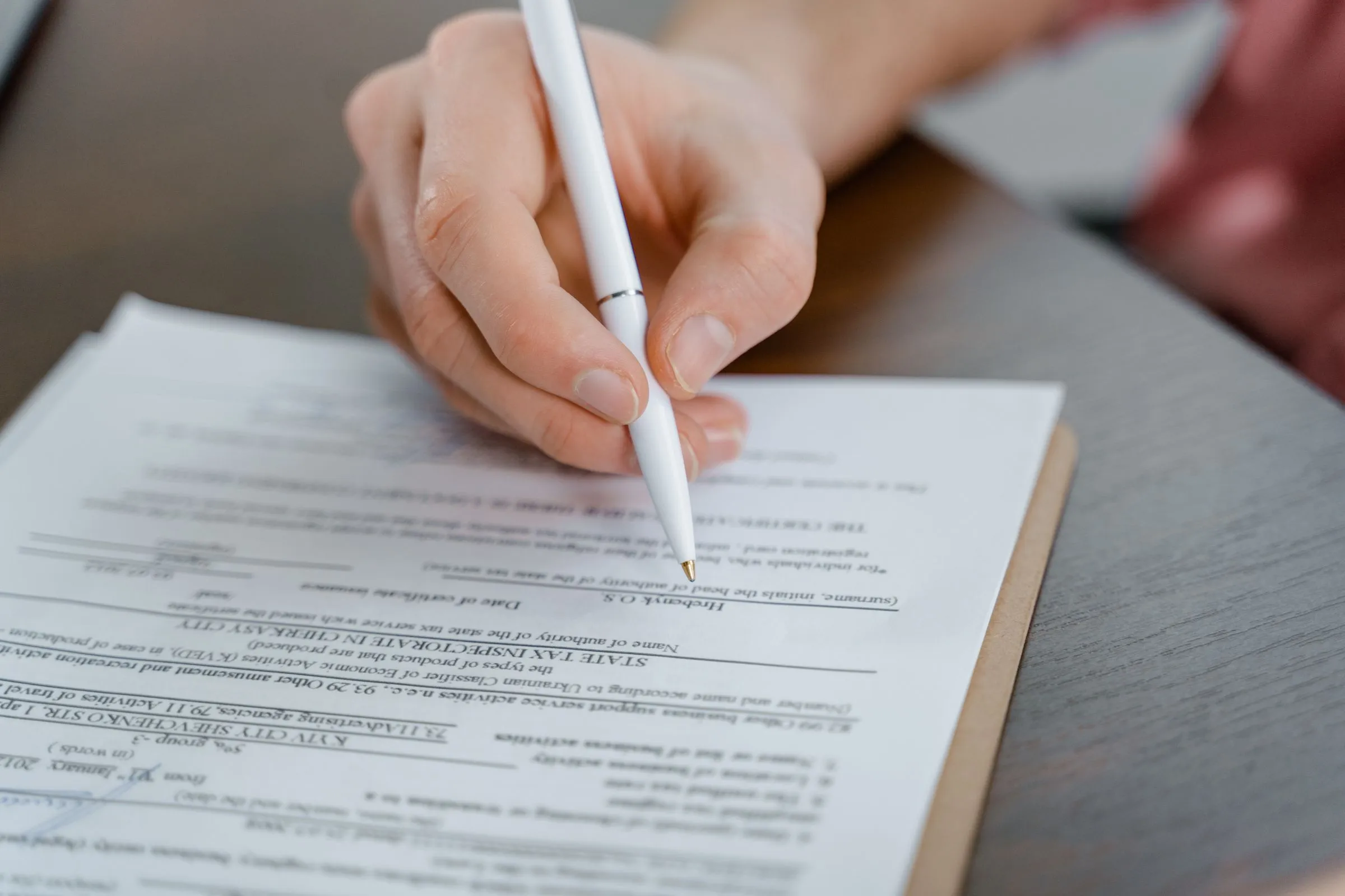Mano firmando un documento con un bolígrafo